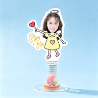 Custom angel girl photo spring bobblehead — sweet girl with a halo and wings in a yellow dress pointing at a heart with Piu Piu stars, acrylic figure bouncing on a spring base
