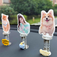 Three custom photo spring bobbleheads displayed on a car dashboard - a cute kitten, a young woman, and a smiling corgi dog