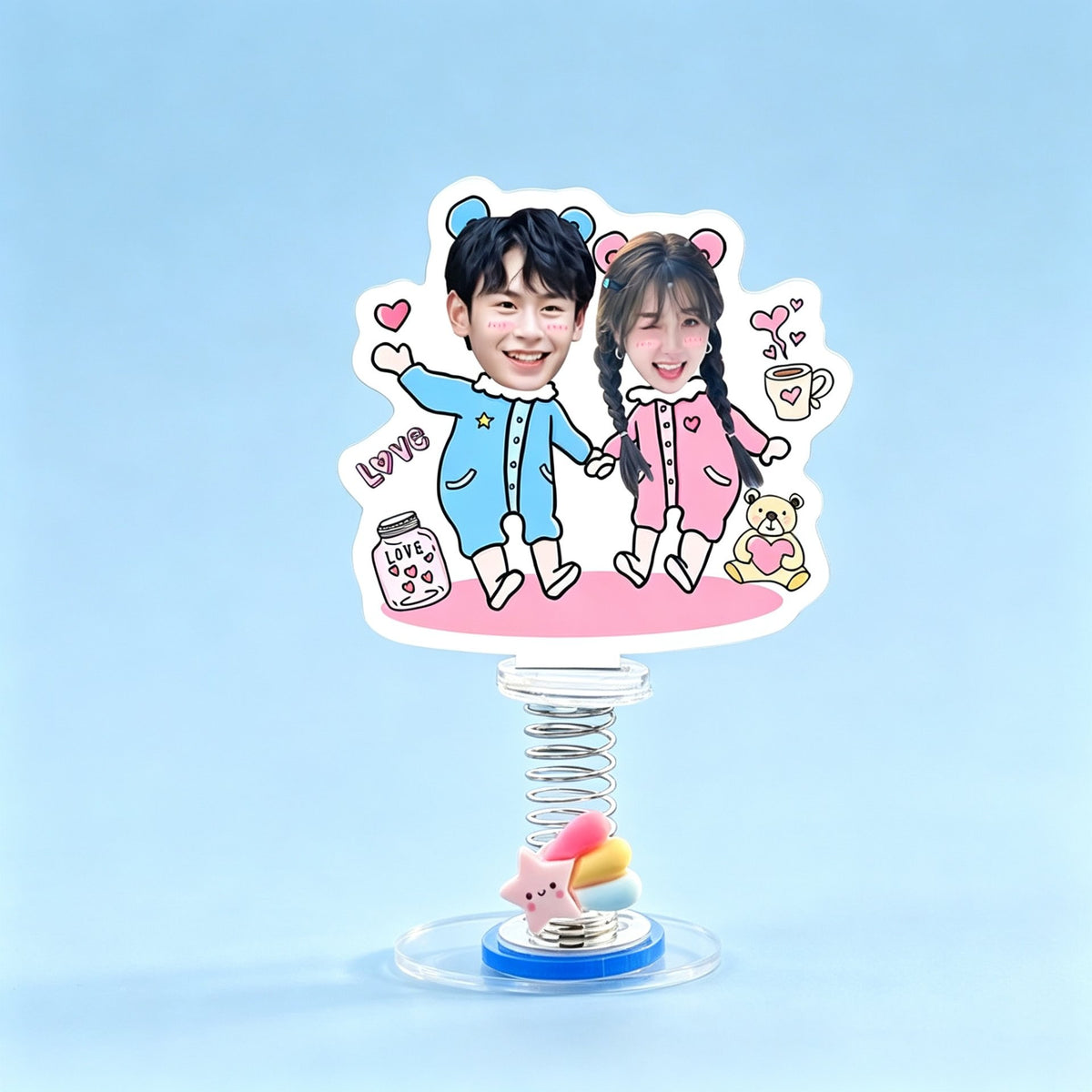 Custom pajama couple photo spring bobblehead — couple in pink and blue onesies holding hands with Love hearts and a teddy bear, acrylic figure bouncing on a spring base