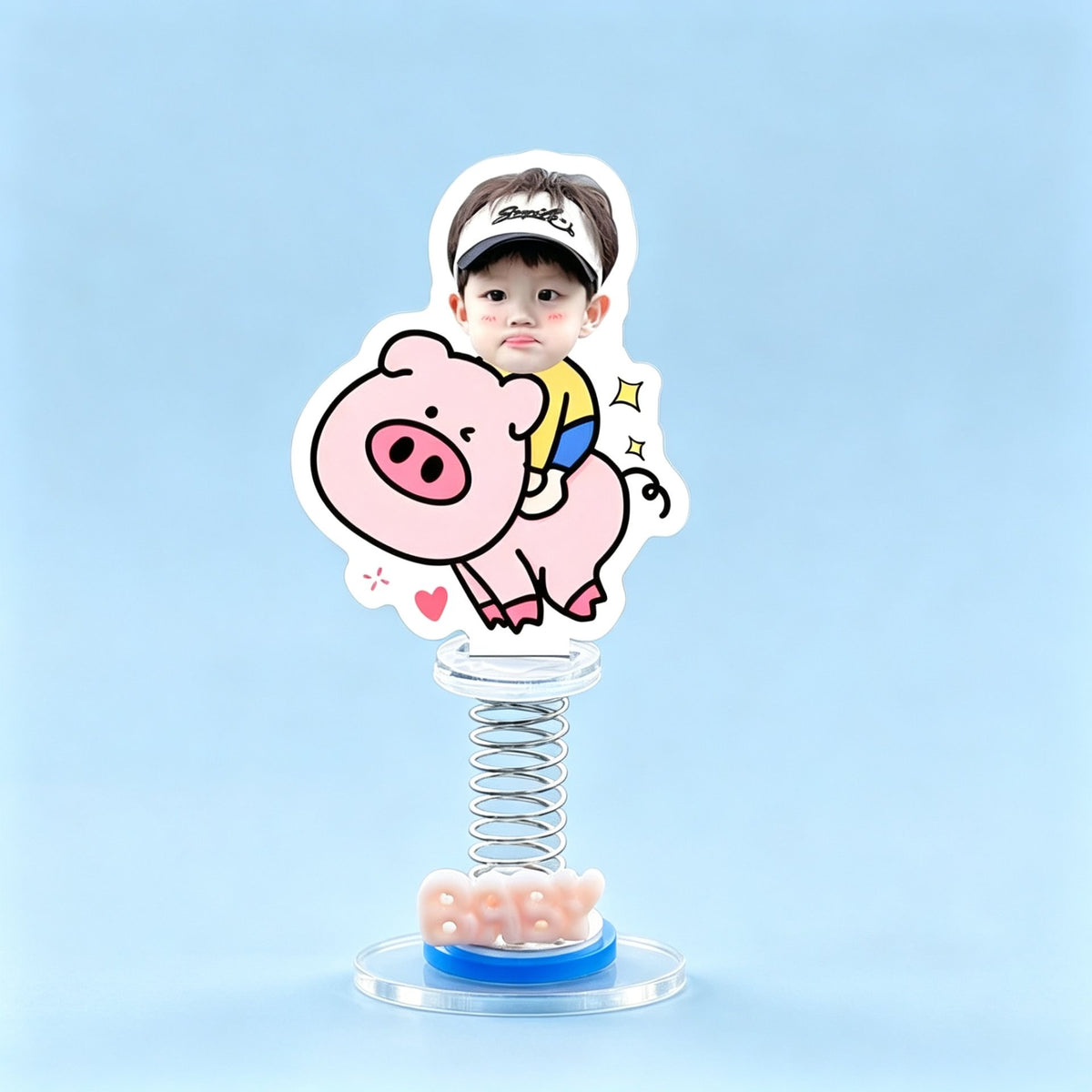 Custom piggy rider photo spring bobblehead — boy in a visor cap riding a chubby pink pig with sparks and a heart, acrylic figure bouncing on a spring base