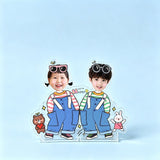Overalls for two custom photo wobble figure — two kids in denim overalls with playful sunglasses and cute bear and bunny charms on a soft blue background, personalized acrylic display that wobbles