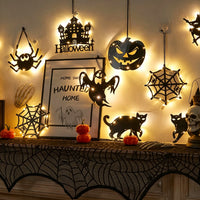 Halloween acrylic wall art lights glowing together on a wall — spider, haunted castle, jack-o'-lantern and spider web silhouettes lit with warm LED fairy lights
