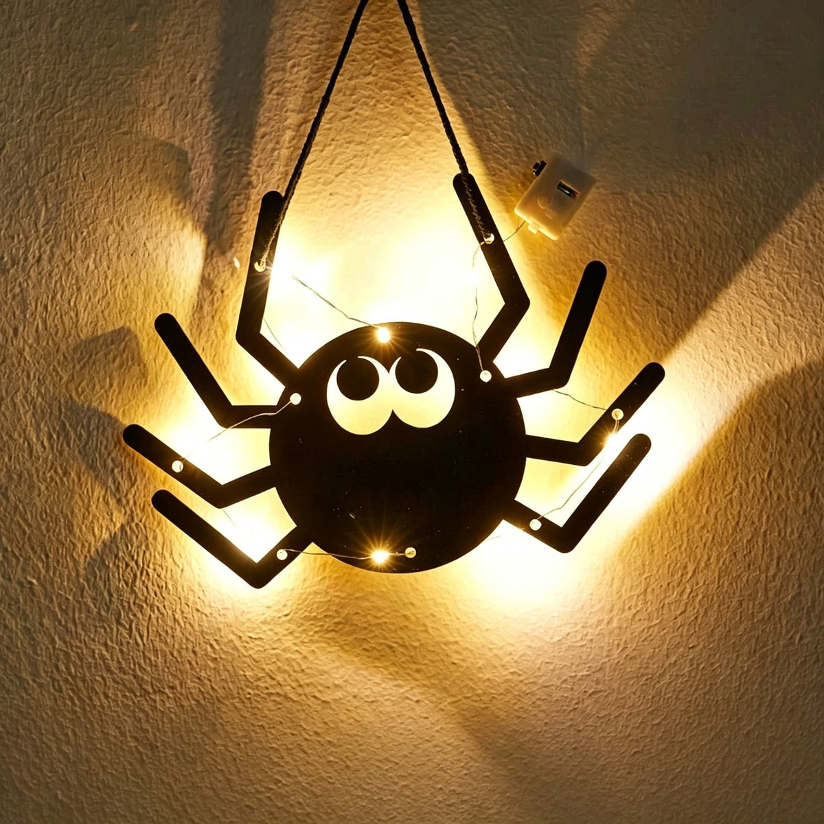 Halloween spider acrylic wall art light — big black spider silhouette with googly eyes glowing with warm LED fairy lights